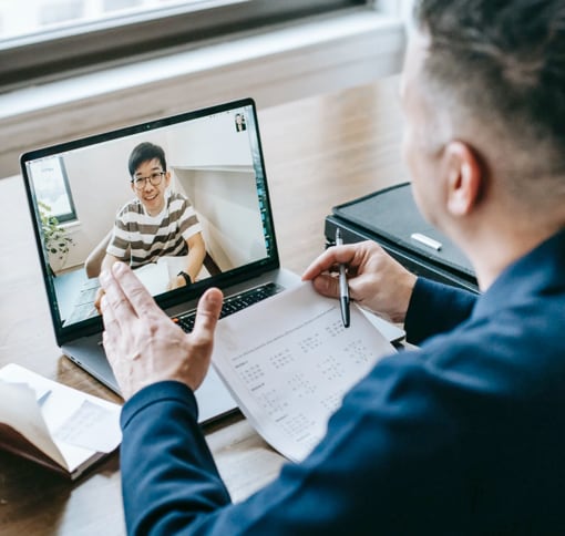 Two men on a video call, one on a laptop screen